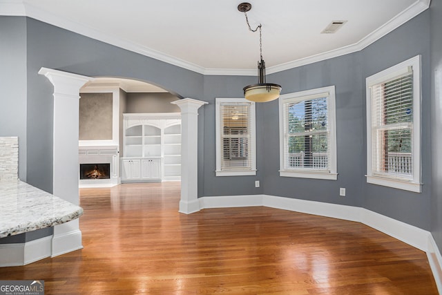 unfurnished dining area with ornamental molding, hardwood / wood-style floors, and decorative columns