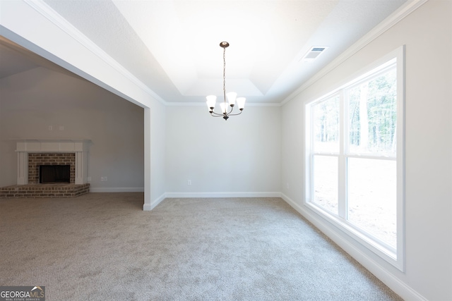 unfurnished dining area featuring a wealth of natural light, a chandelier, a brick fireplace, and carpet floors