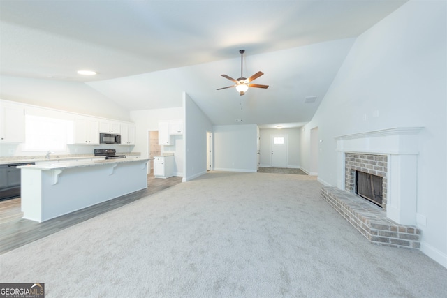 unfurnished living room with light hardwood / wood-style flooring, ceiling fan, lofted ceiling, and a fireplace