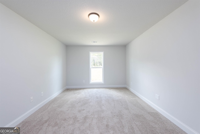 carpeted empty room featuring a textured ceiling