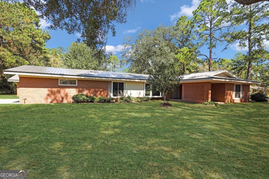 back of house with a lawn and brick siding