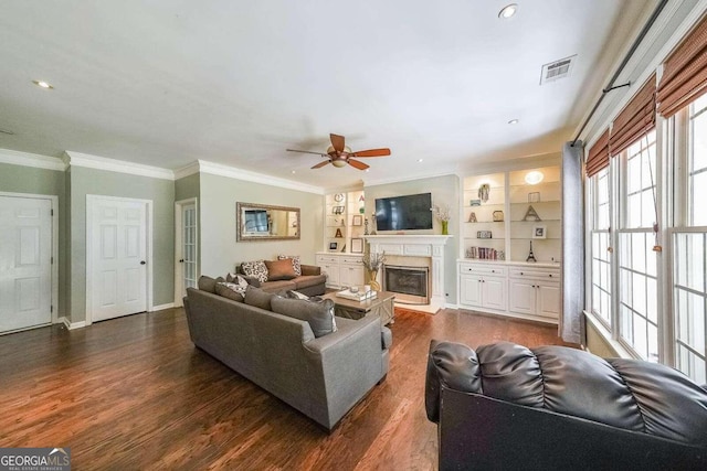 living room with crown molding, dark wood-type flooring, ceiling fan, and built in shelves