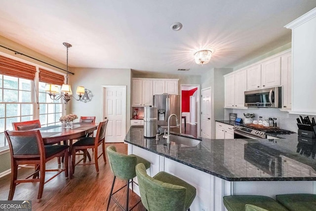 kitchen with pendant lighting, sink, dark wood-type flooring, stainless steel appliances, and white cabinets