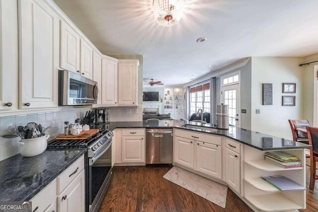 kitchen with white cabinetry, tasteful backsplash, appliances with stainless steel finishes, dark hardwood / wood-style floors, and kitchen peninsula