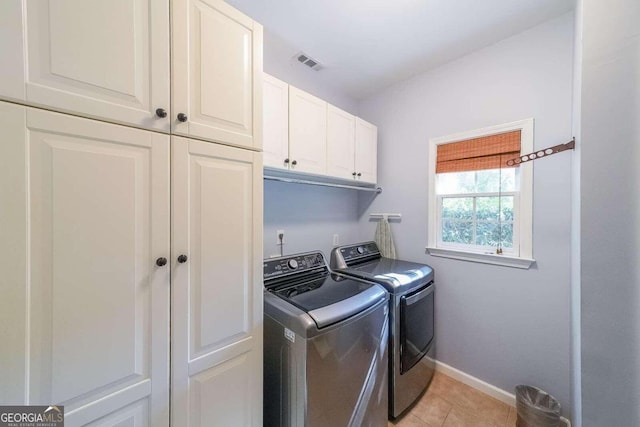 laundry area featuring cabinets, light tile patterned flooring, and washer and dryer