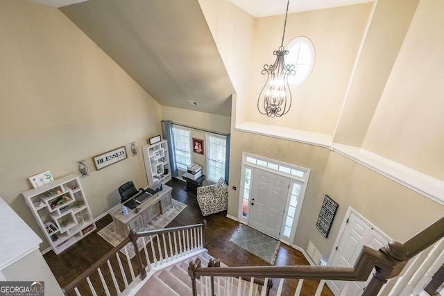 foyer featuring dark wood-type flooring, a towering ceiling, and a notable chandelier