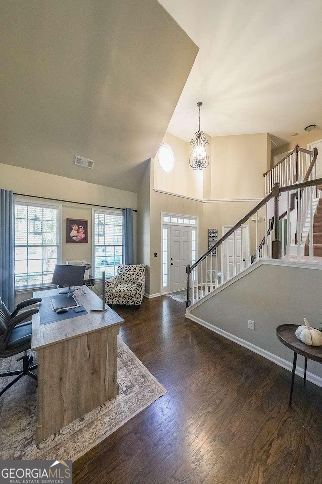 foyer entrance with dark hardwood / wood-style flooring, lofted ceiling, and an inviting chandelier