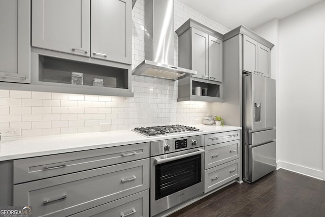 kitchen with wall chimney range hood, an island with sink, stainless steel appliances, a breakfast bar, and pendant lighting