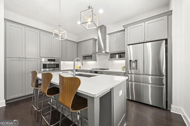 kitchen featuring decorative backsplash, wall chimney range hood, dark wood-type flooring, gray cabinetry, and stainless steel appliances