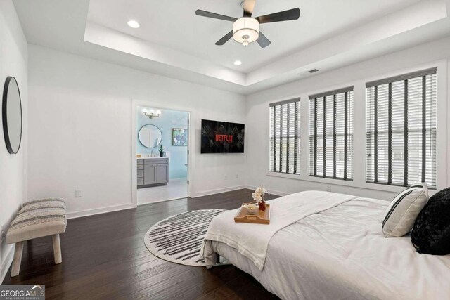 bedroom featuring dark wood-type flooring, a tray ceiling, and ceiling fan