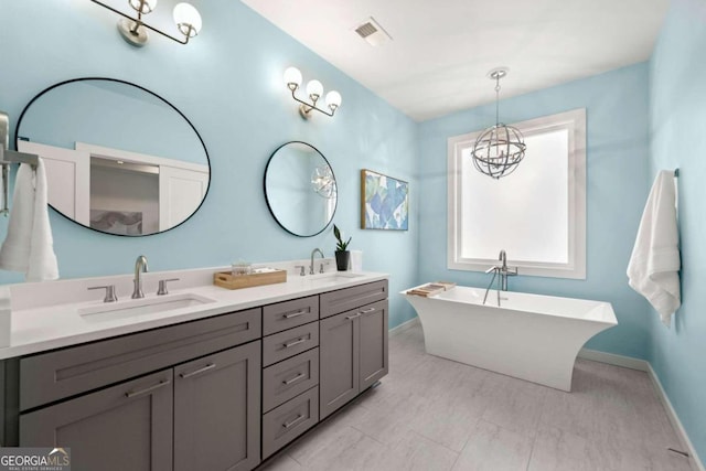 bathroom featuring vanity, a notable chandelier, and a washtub