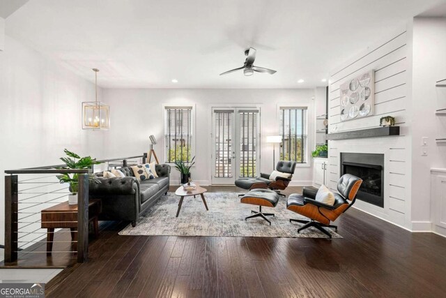 living room featuring dark wood-type flooring and ceiling fan with notable chandelier