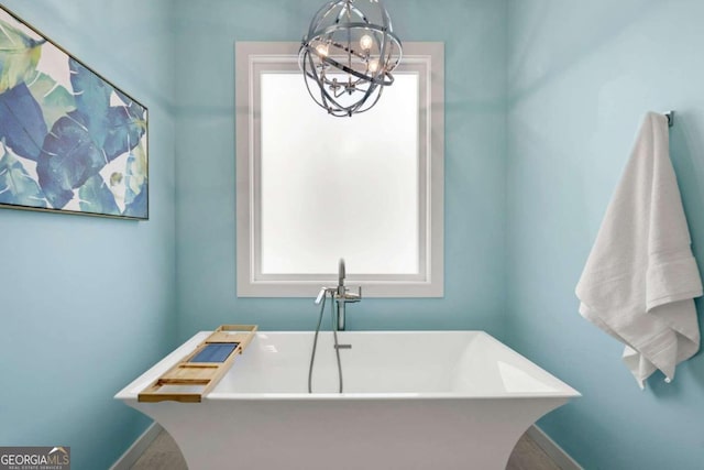 bathroom with an inviting chandelier and a bathtub