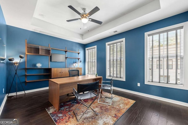 office area featuring ceiling fan, dark hardwood / wood-style floors, and a raised ceiling