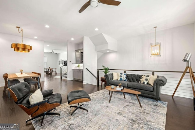 living room featuring dark wood-type flooring and ceiling fan with notable chandelier