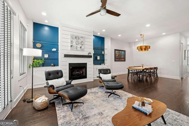 living room featuring ceiling fan, a fireplace, and dark hardwood / wood-style flooring