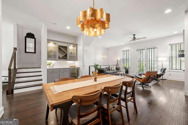 dining area featuring wine cooler, dark wood-type flooring, and ceiling fan with notable chandelier