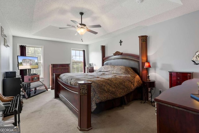 carpeted bedroom with ceiling fan, a textured ceiling, and a tray ceiling