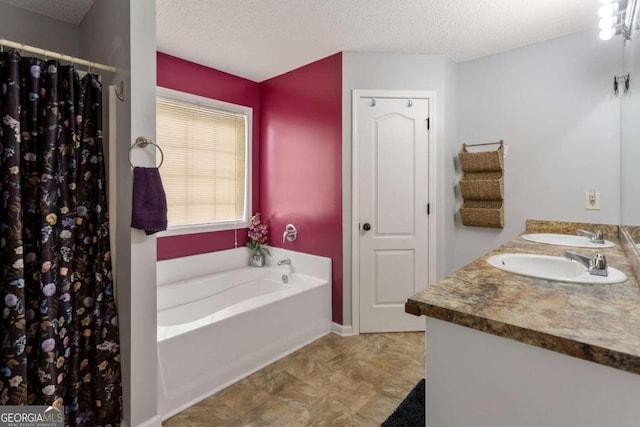 bathroom featuring vanity, a textured ceiling, and a bathtub