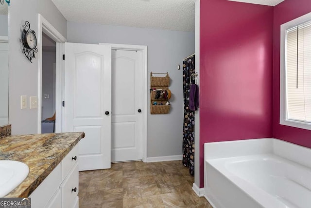 bathroom featuring vanity, a bathtub, a textured ceiling, and plenty of natural light