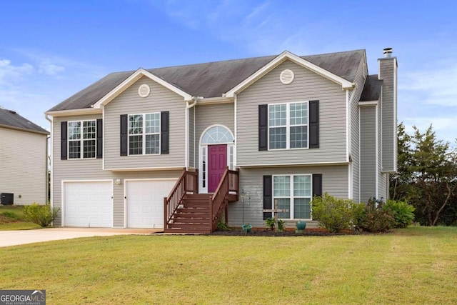 bi-level home featuring a garage, a front lawn, and central AC unit