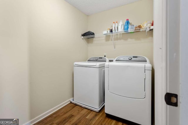 laundry area with a textured ceiling, separate washer and dryer, and dark hardwood / wood-style flooring