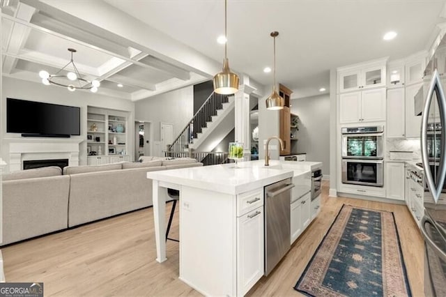 kitchen with a breakfast bar area, appliances with stainless steel finishes, an island with sink, and white cabinets