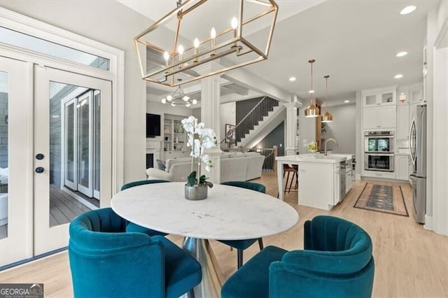 dining space featuring light hardwood / wood-style floors, french doors, sink, and an inviting chandelier