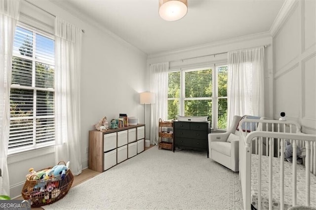 carpeted bedroom with multiple windows, ornamental molding, and a crib