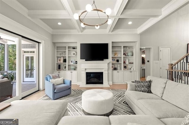 living room with coffered ceiling, beamed ceiling, ornamental molding, a notable chandelier, and light hardwood / wood-style floors