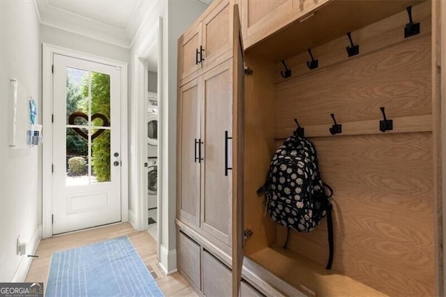 mudroom with crown molding, stacked washer / dryer, and light hardwood / wood-style floors