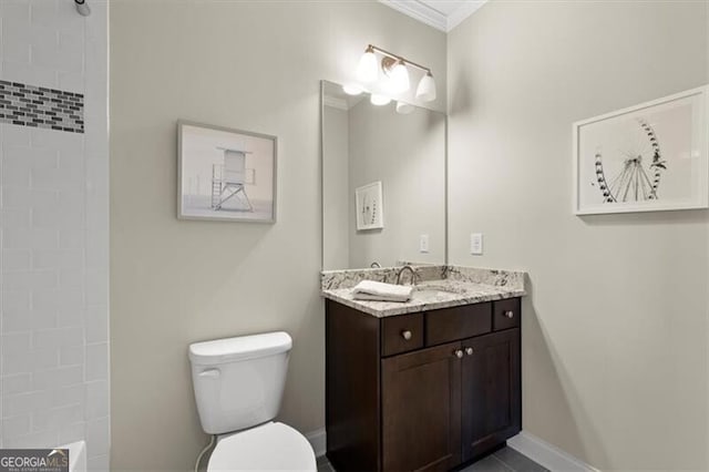 bathroom featuring toilet, ornamental molding, vanity, and a tile shower