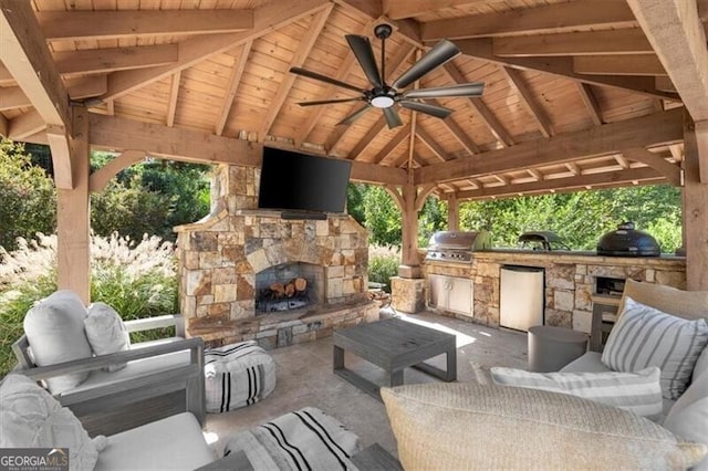 view of patio / terrace with exterior kitchen, a gazebo, ceiling fan, an outdoor living space with a fireplace, and a grill