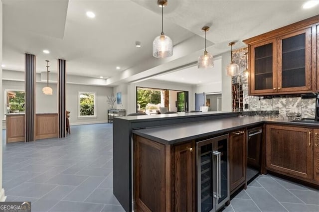 interior space with backsplash, kitchen peninsula, dark tile patterned floors, decorative light fixtures, and beverage cooler