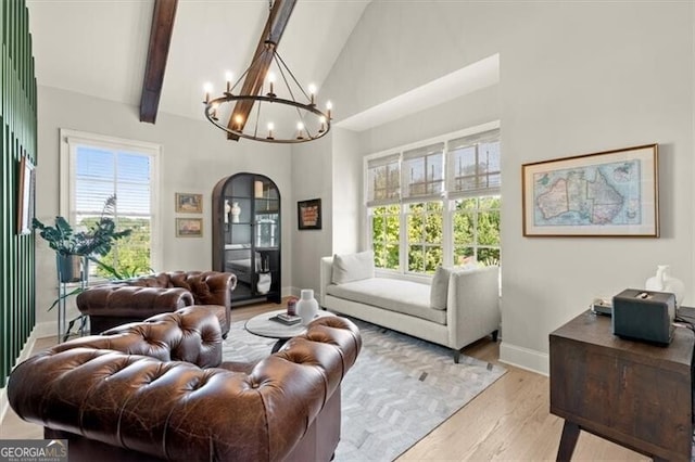 living room featuring a notable chandelier, high vaulted ceiling, light wood-type flooring, and plenty of natural light