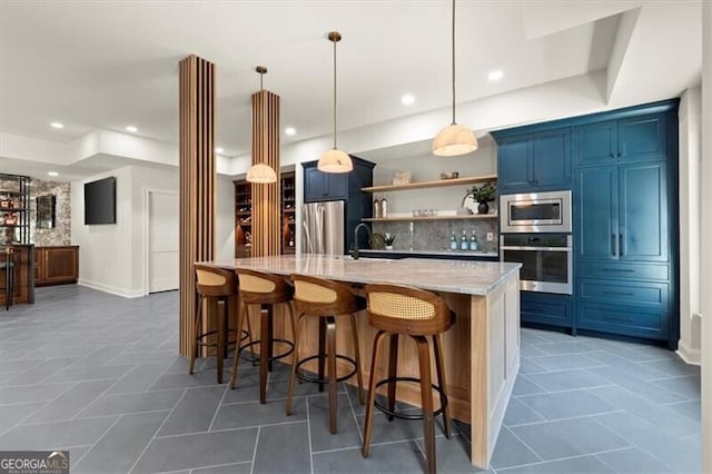 kitchen featuring hanging light fixtures, a breakfast bar area, light stone countertops, blue cabinetry, and stainless steel appliances