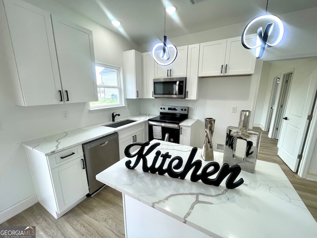 kitchen featuring white cabinets, decorative light fixtures, stainless steel appliances, and sink