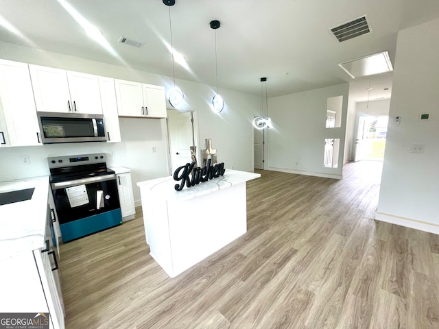 kitchen with white cabinets, appliances with stainless steel finishes, pendant lighting, a kitchen island, and light wood-type flooring