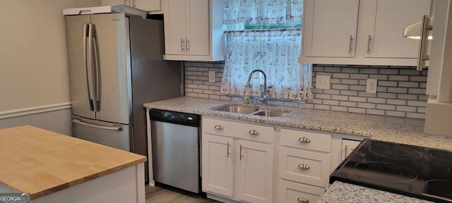 kitchen with tasteful backsplash, light stone countertops, appliances with stainless steel finishes, sink, and white cabinets