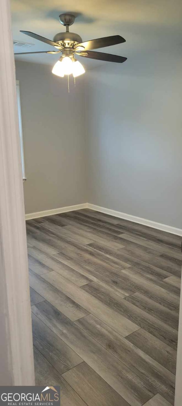 spare room with dark wood-type flooring and ceiling fan