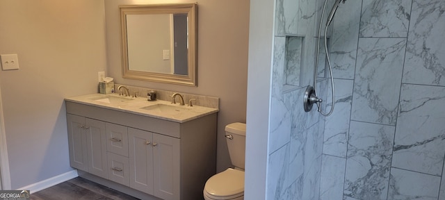 bathroom with vanity, toilet, wood-type flooring, and a tile shower