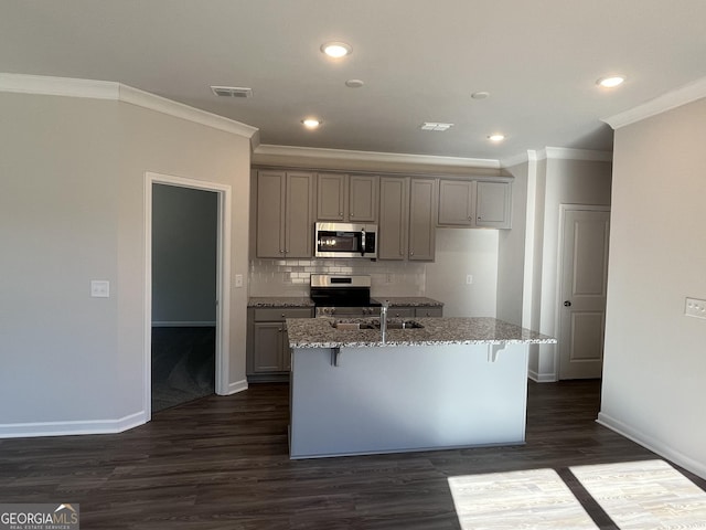 kitchen featuring a kitchen island with sink, light stone countertops, gray cabinetry, stainless steel appliances, and dark hardwood / wood-style flooring