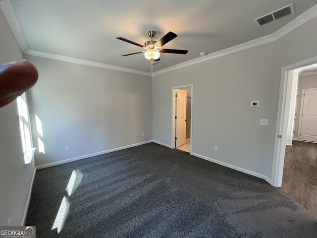 empty room with ceiling fan, crown molding, and dark carpet