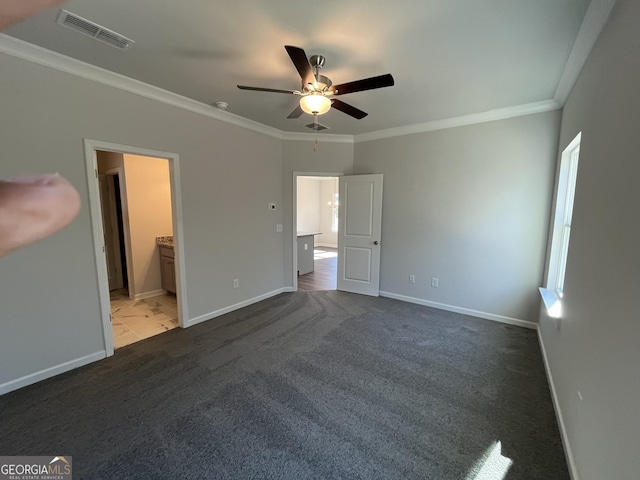 unfurnished bedroom with ensuite bathroom, ceiling fan, crown molding, multiple windows, and dark carpet