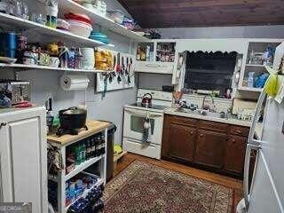 kitchen featuring sink, dark brown cabinetry, dark wood-type flooring, and white electric stove