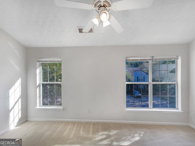 empty room featuring light carpet, a textured ceiling, and ceiling fan