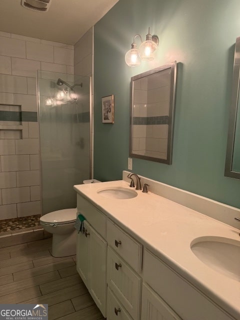 bathroom with vanity, toilet, and tiled shower