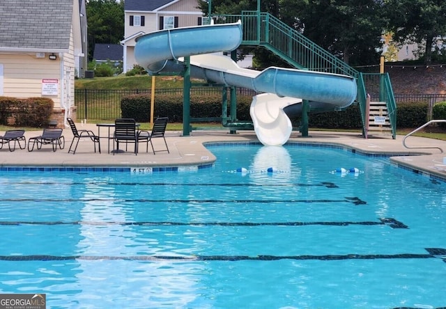 view of swimming pool with a water slide and a patio area