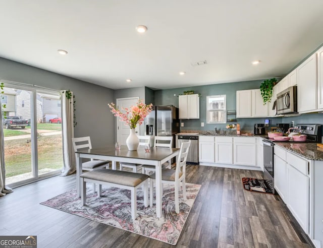 kitchen with appliances with stainless steel finishes, dark hardwood / wood-style floors, white cabinetry, and dark stone counters