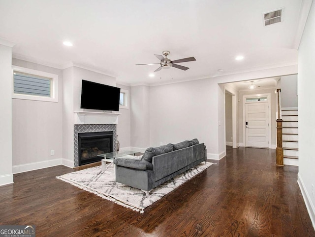 living room with crown molding, a fireplace, dark hardwood / wood-style floors, and ceiling fan